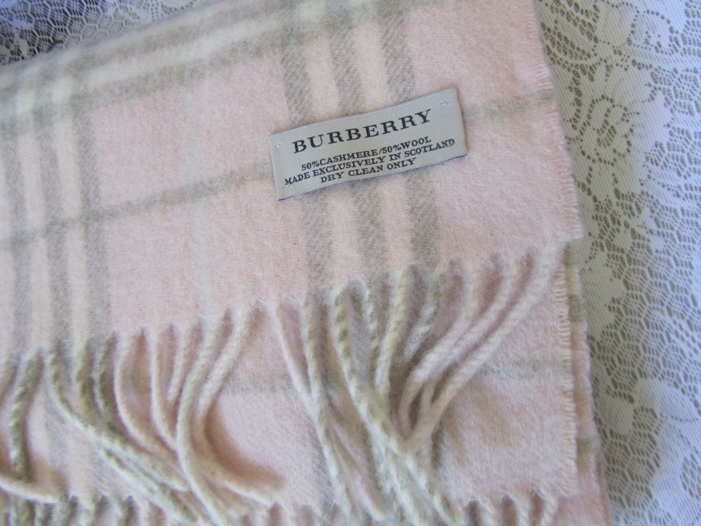 Plaid scarf with a brand label on a textured white surface