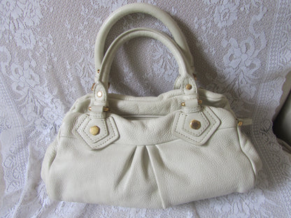 Light-colored handbag on a textured white background
