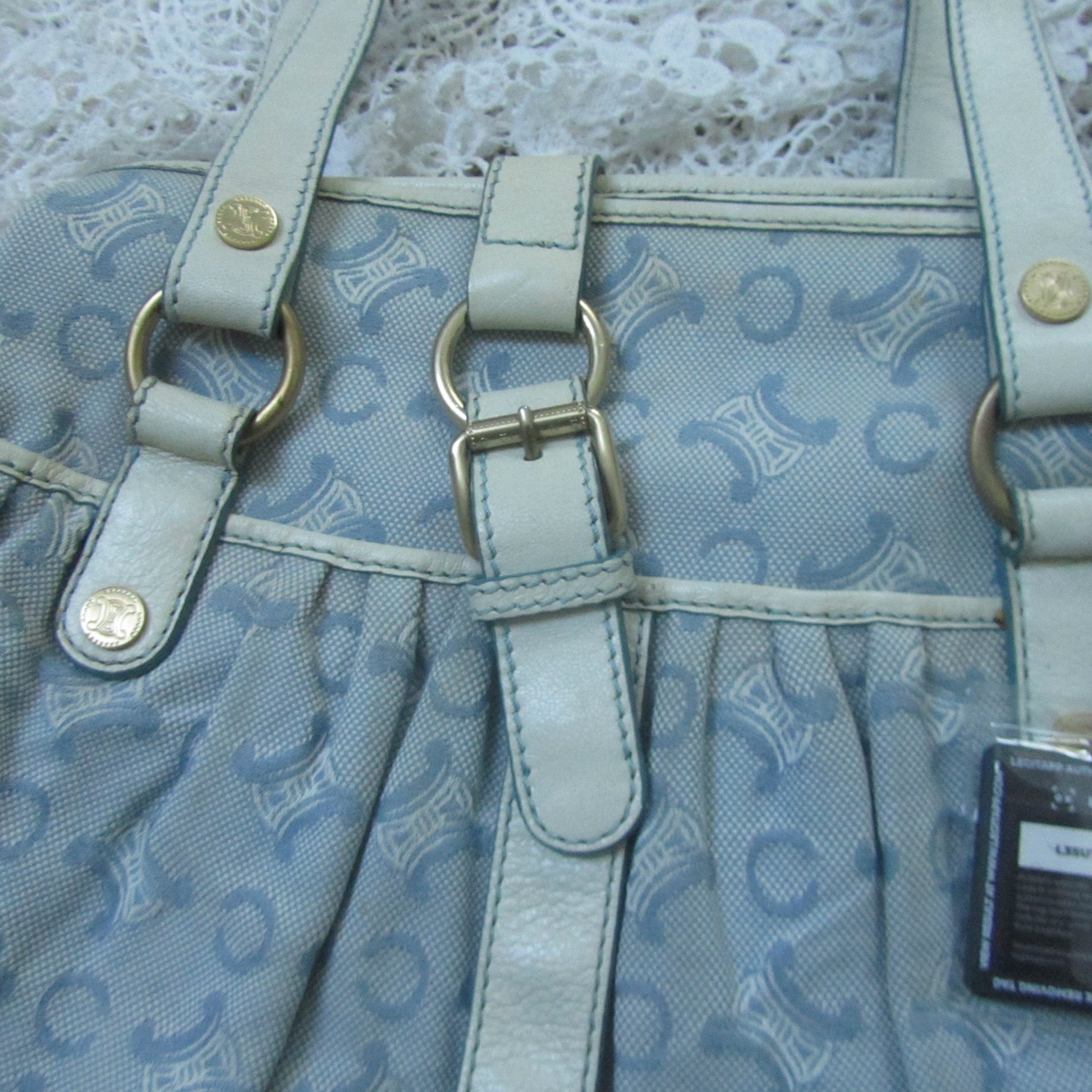Light blue handbag with a pattern and visible brand tag on a textured white background