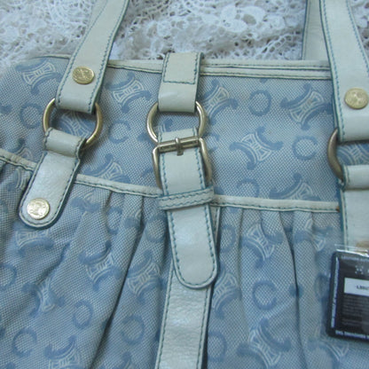 Light blue handbag with a pattern and visible brand tag on a textured white background