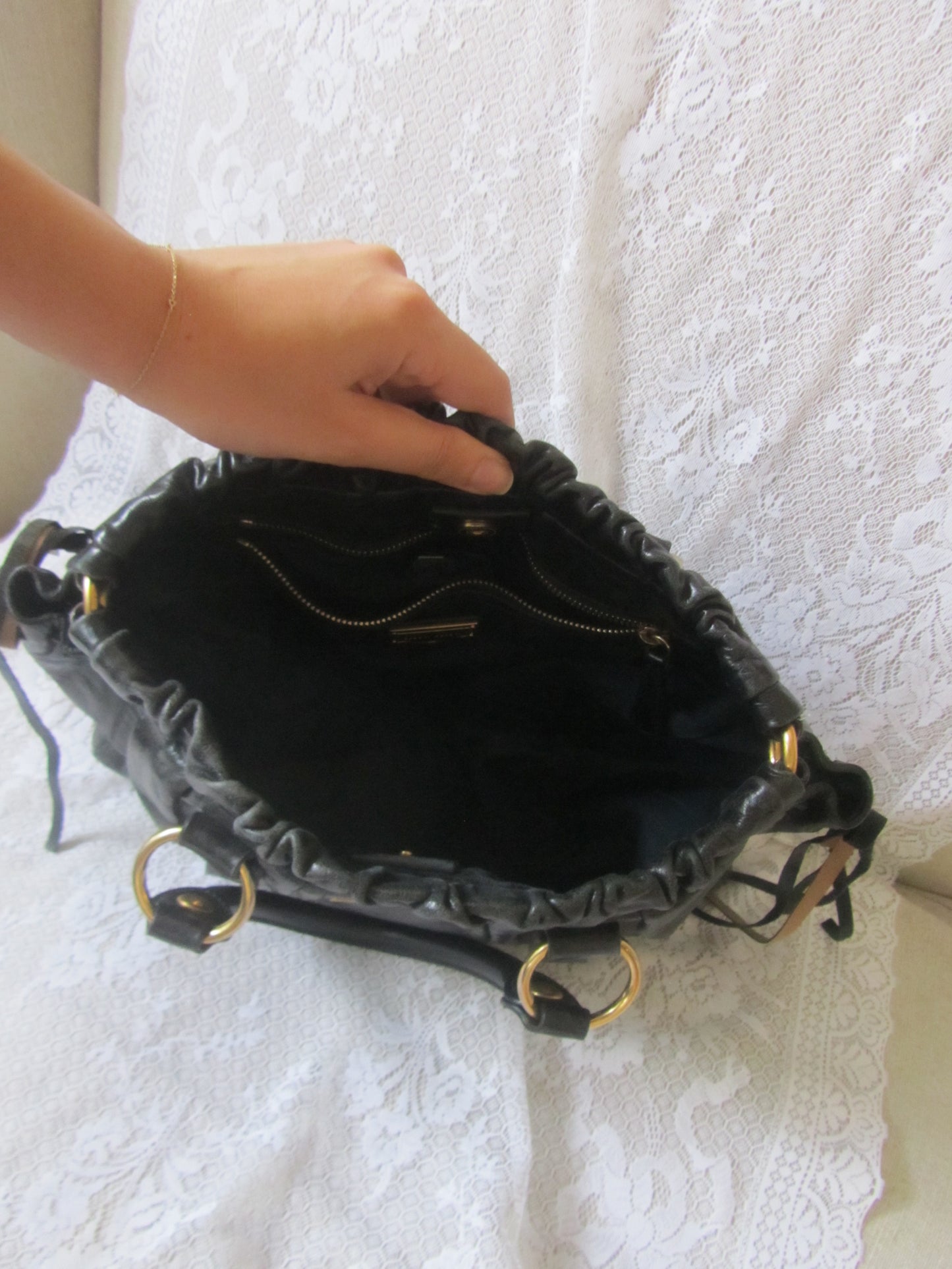 Black handbag with gold accents on a white textured surface