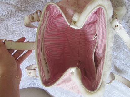 Close-up of a pink handbag with a textured interior, held by a hand on a light background.