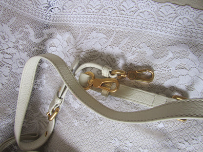 White leather strap with gold hardware on a lace background