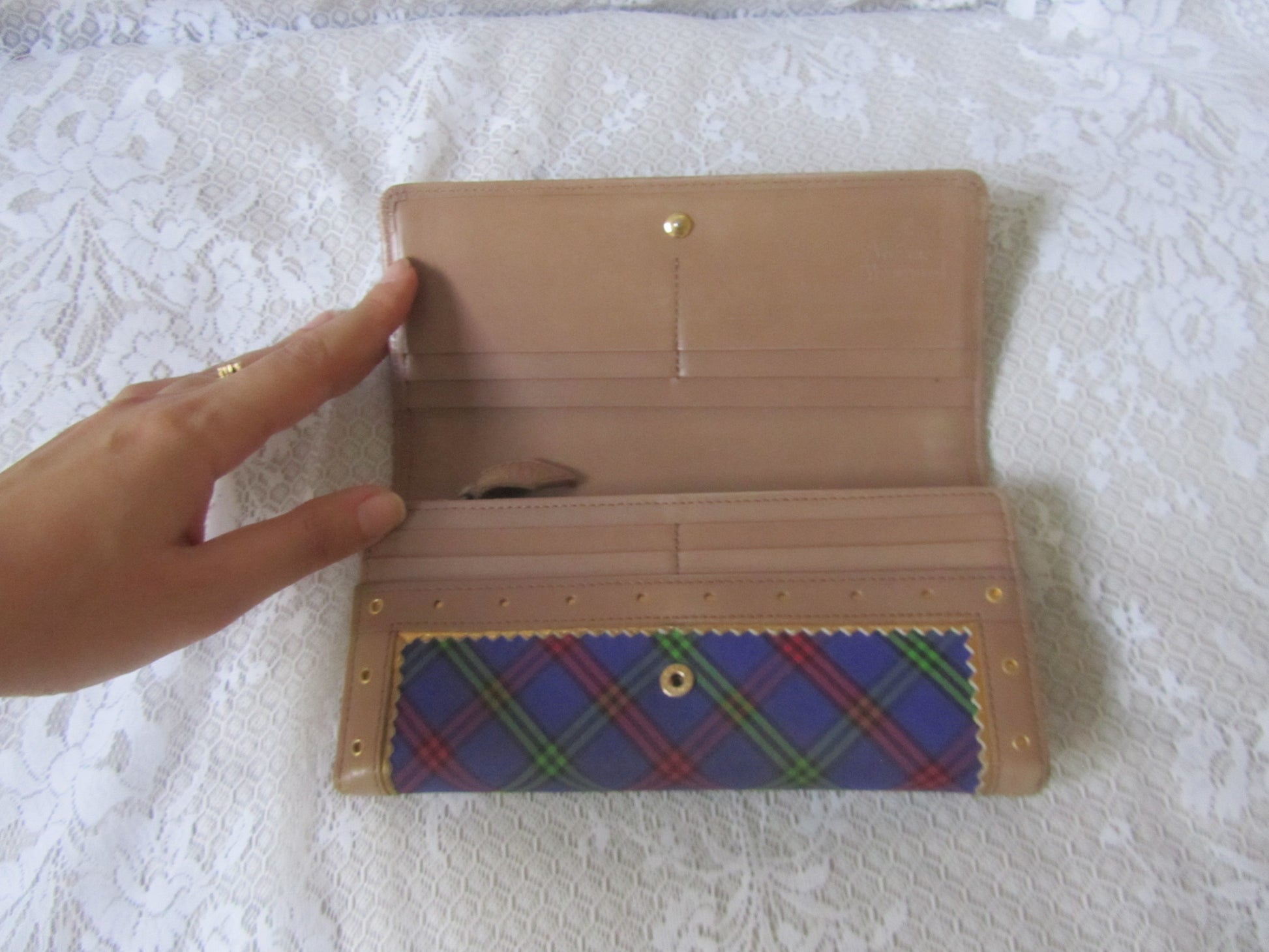 Beige wallet with plaid interior on a textured white surface
