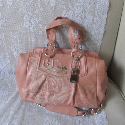 Pink handbag with decorative elements on a textured surface