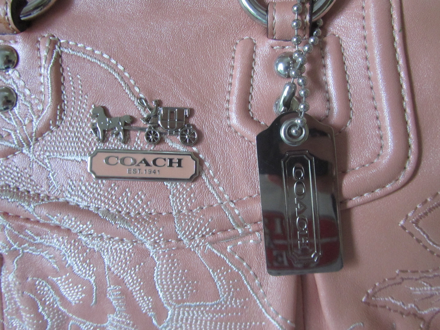 Close-up of a Coach handbag with branding and keychain.
