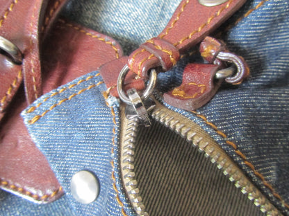 Close-up of a leather strap attached to a zipper on denim fabric.