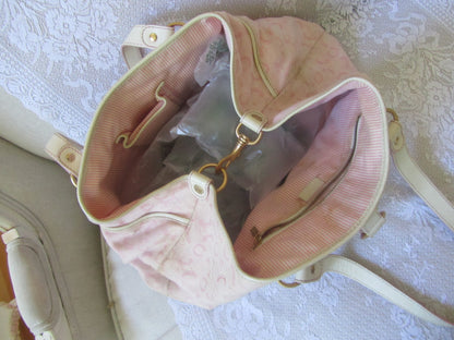 Pink handbag with gold accents on a textured surface