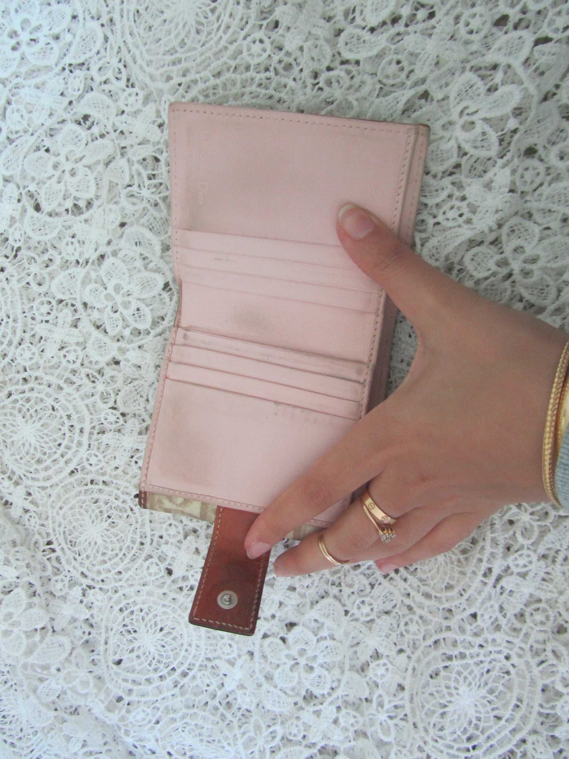 Hand holding a pink wallet on a textured white surface