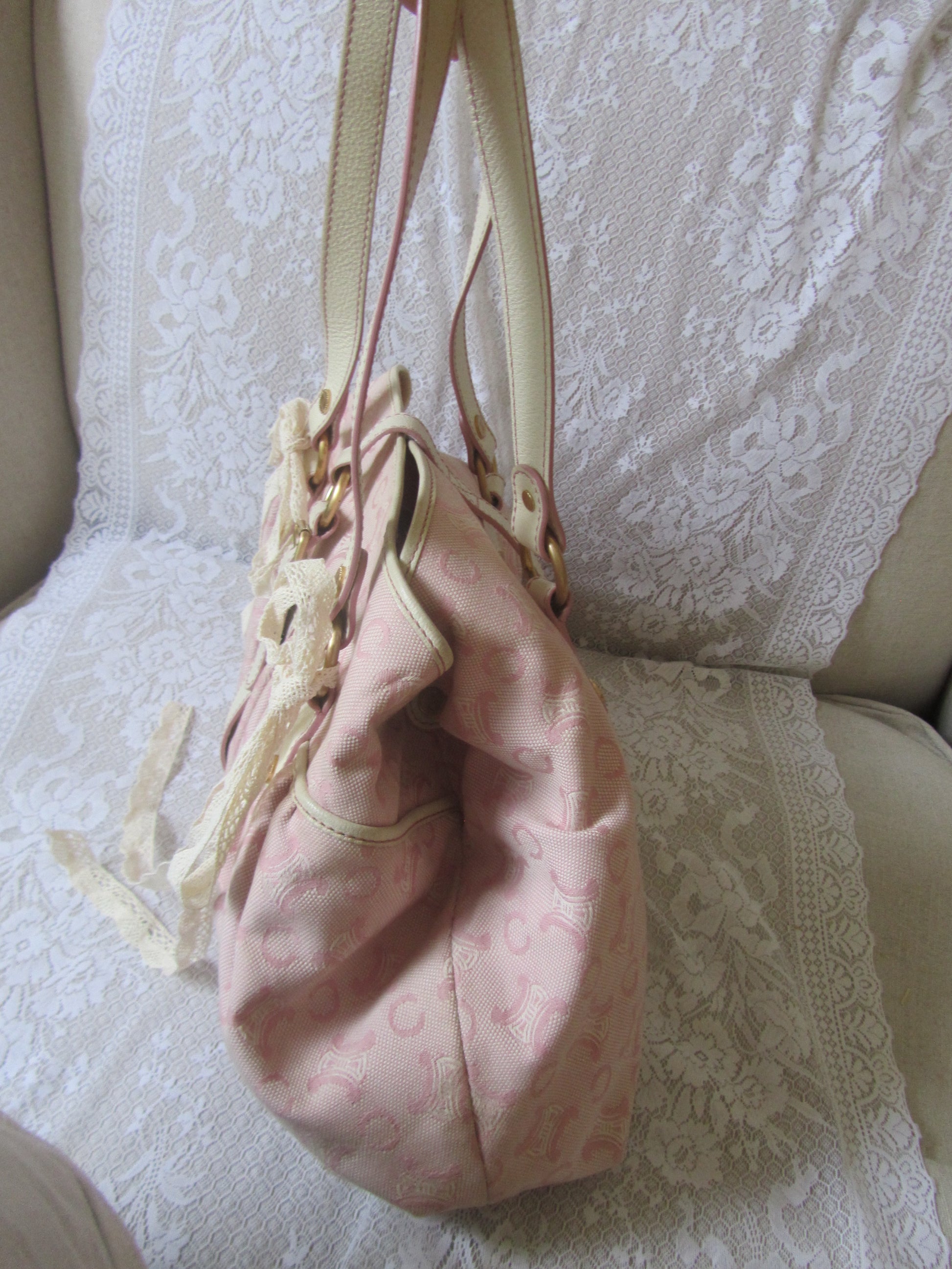 Pink handbag with gold handle on a textured surface