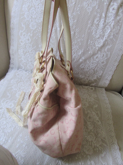 Pink handbag with gold handle on a textured surface