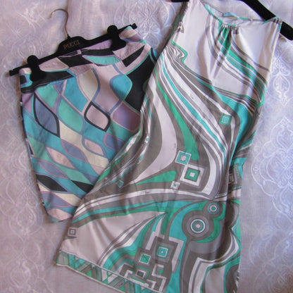 Two patterned dresses on hangers against a textured white background