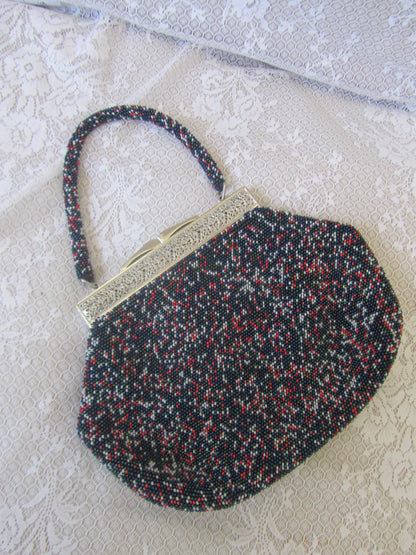 Multicolored beaded handbag with a gold clasp on a textured surface