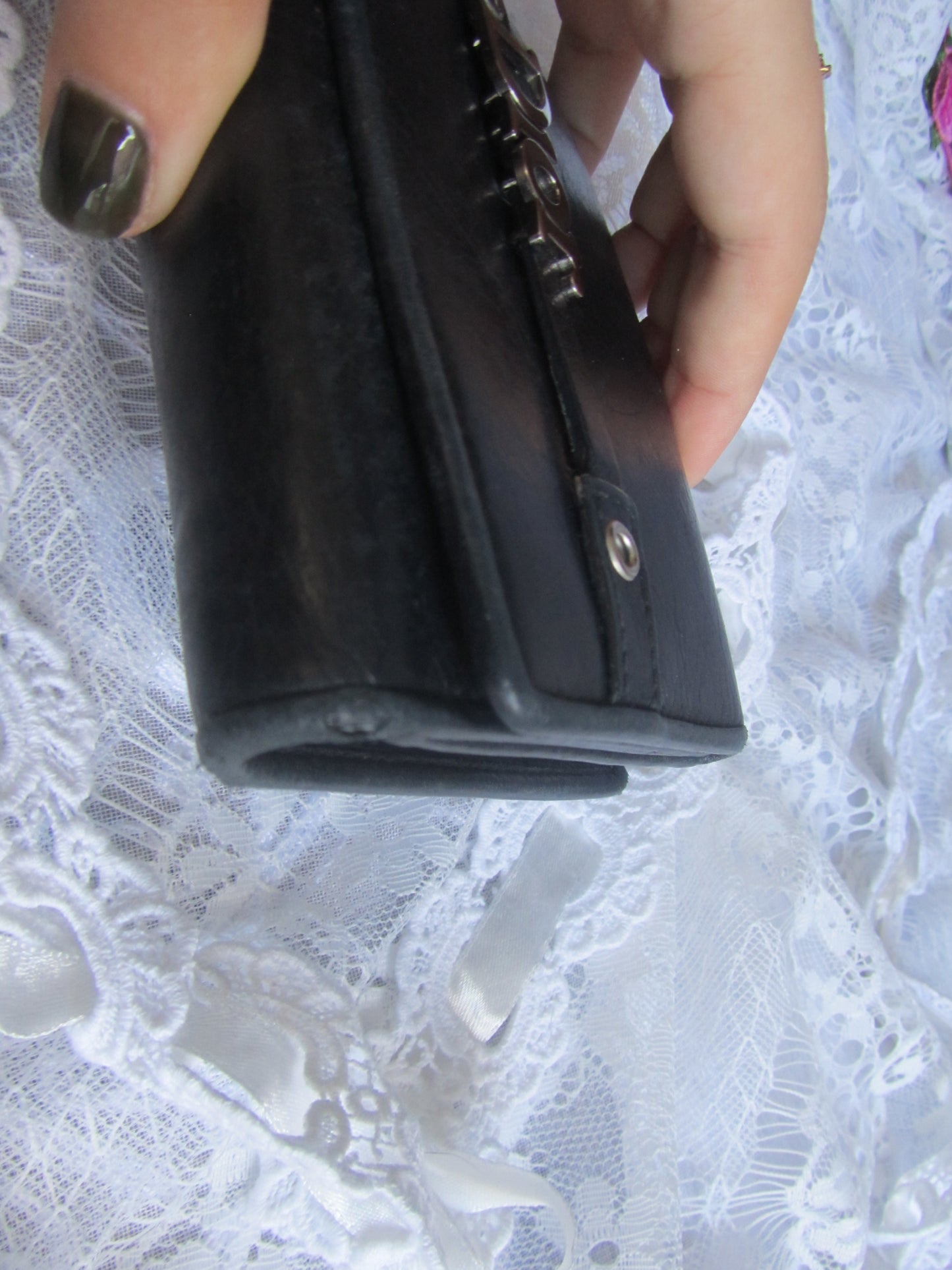 Black wallet held by a hand on a white lace background