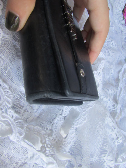 Black wallet held by a hand on a white lace background