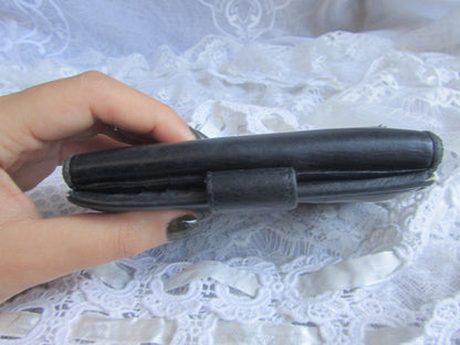 Hand holding a black wallet against a white lace background