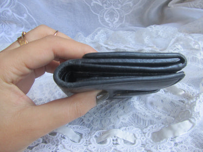 Hand holding a black wallet against a white lace background