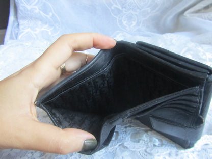 Hand holding an empty black wallet against a textured white background