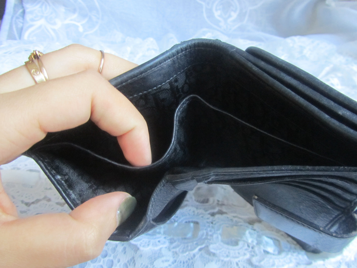 Person holding an open black wallet against a textured white background