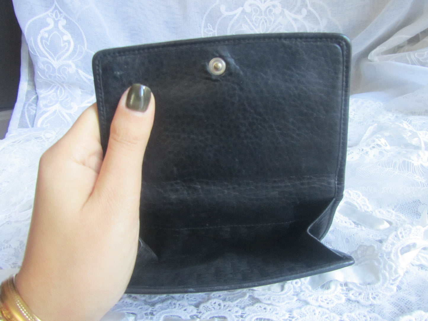 Black wallet held by a hand with a blurred background