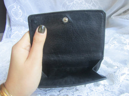Black wallet held by a hand with a blurred background