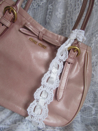 Pink handbag with lace trim on a white lace background