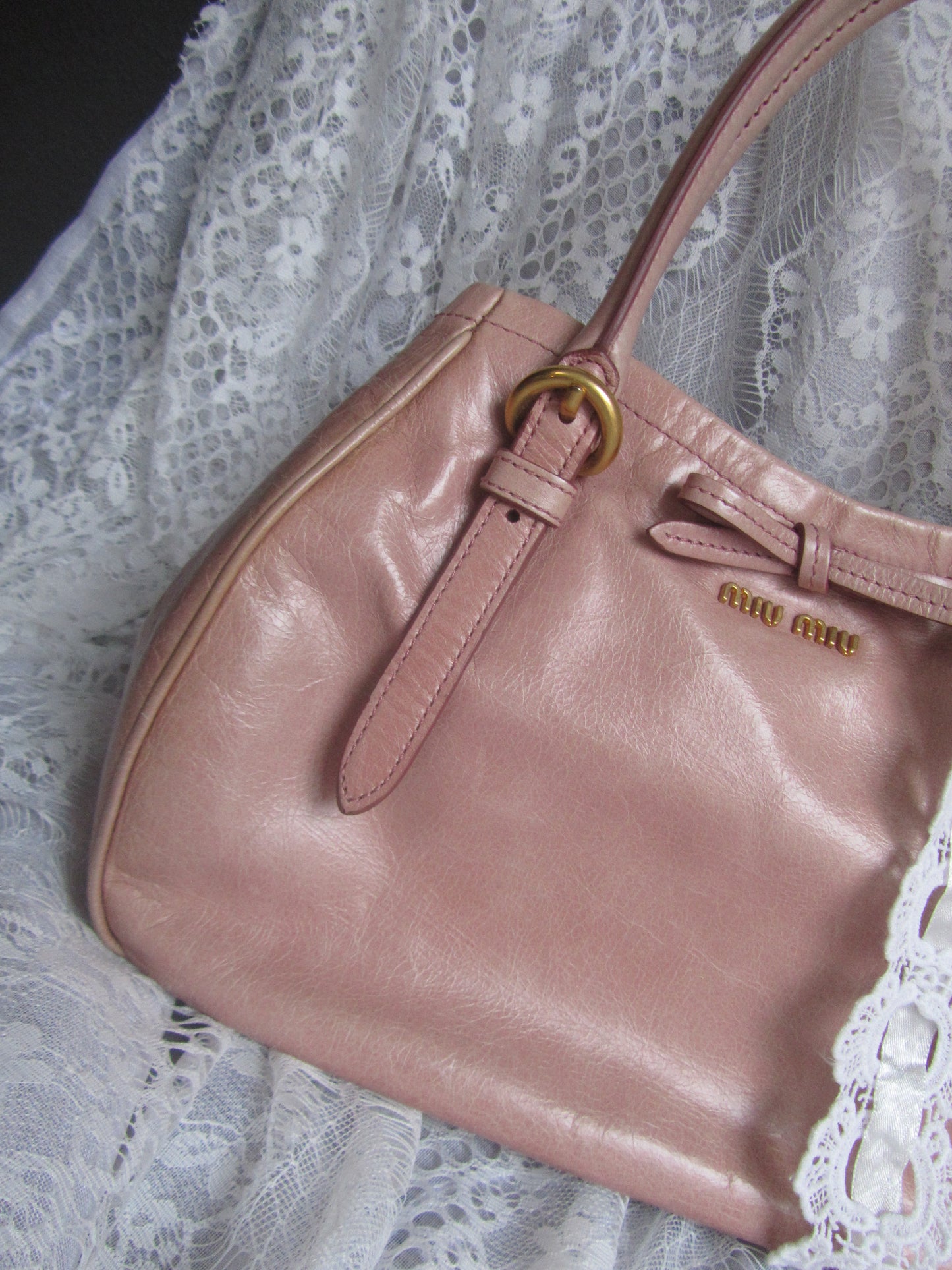 Pink handbag with gold buckle on a lace background