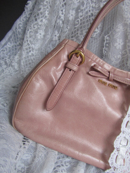 Pink handbag with gold buckle on a lace background