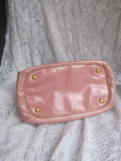 Pink leather clutch with gold studs on a lace fabric background