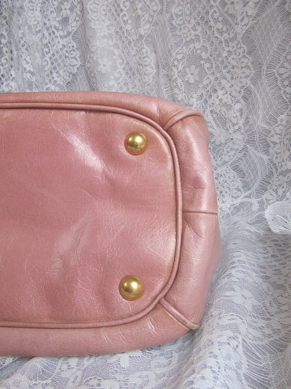 Pink leather bag with gold studs on a lace background