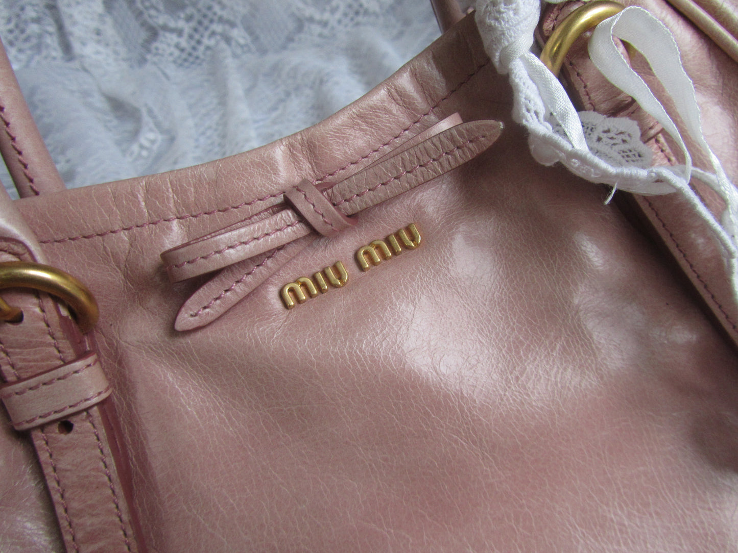 Close-up of a pink handbag with gold hardware and 'MIU MIU' logo.