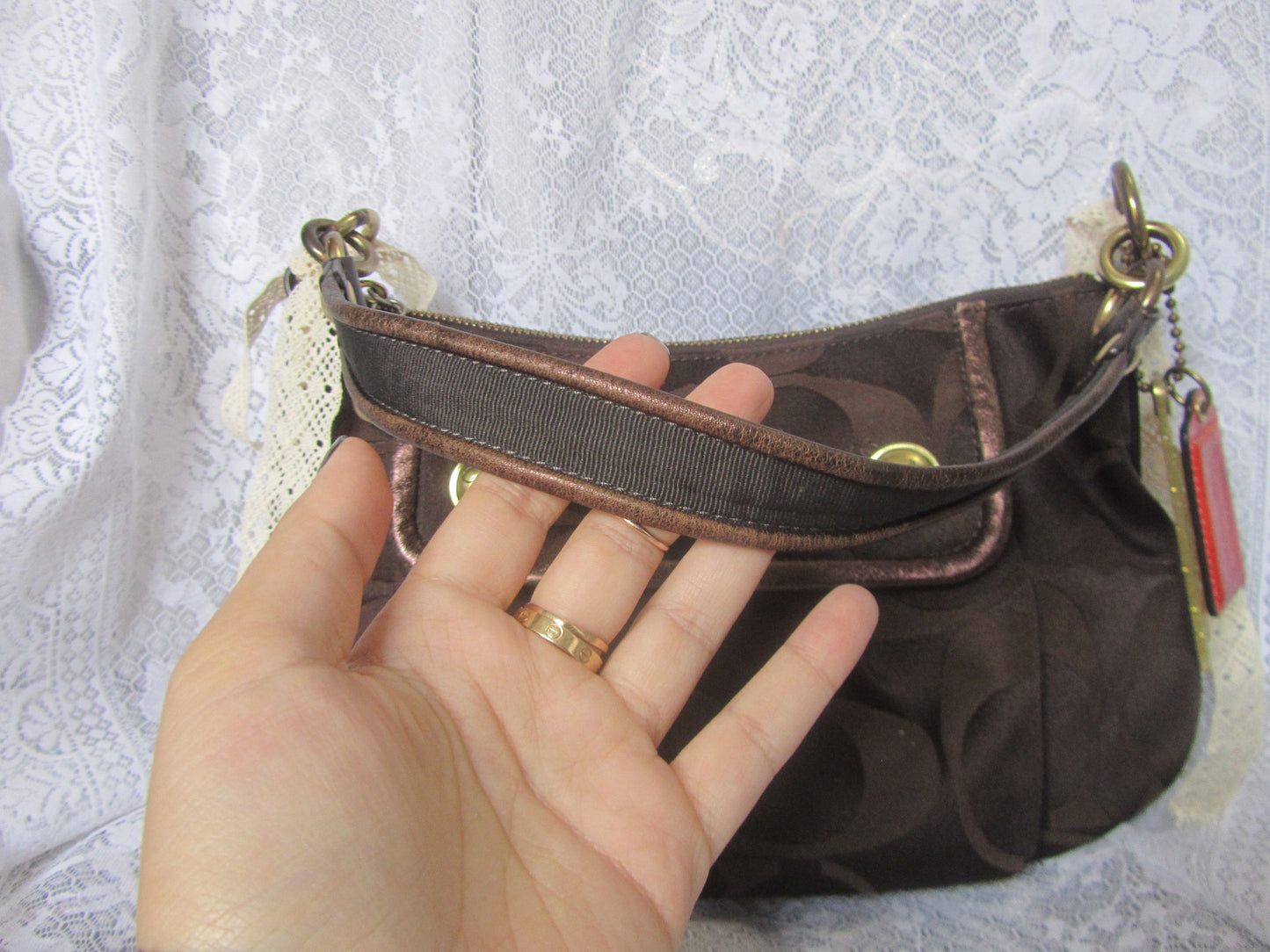 Brown handbag held by a hand against a textured white background