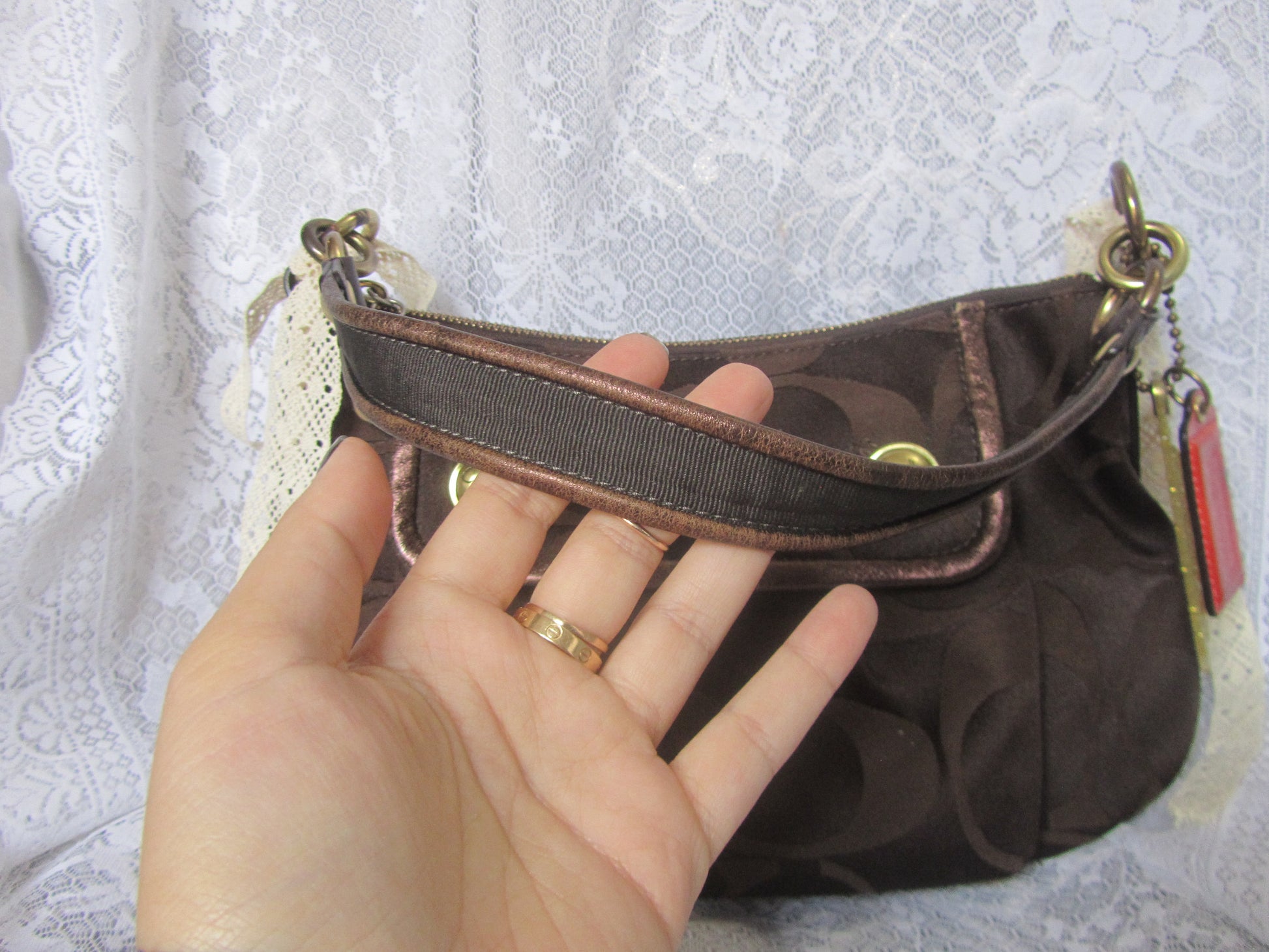 Brown handbag held by a hand against a textured white background