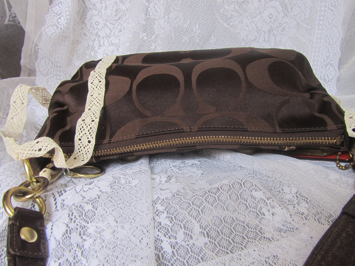 Brown handbag with gold zipper on a white lace background