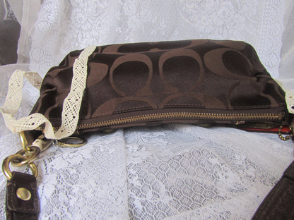 Brown handbag with gold zipper on a white lace background