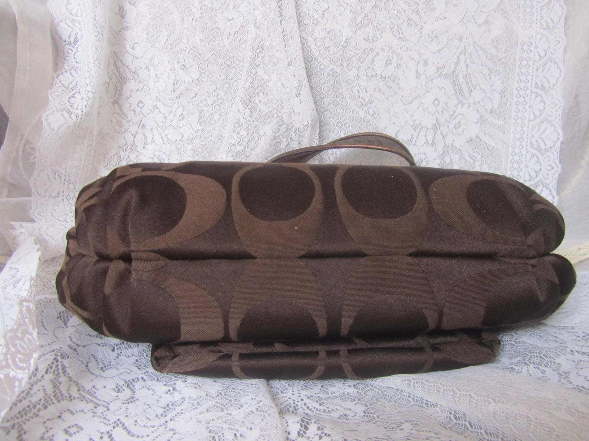Brown textured bag on a white lace fabric background