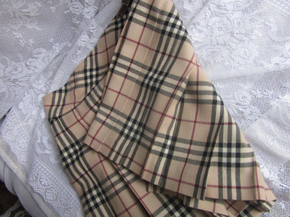 Plaid fabric with beige, black, and red pattern on a textured white background