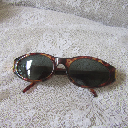 Sunglasses with tortoiseshell frame and dark lenses on a lace fabric background