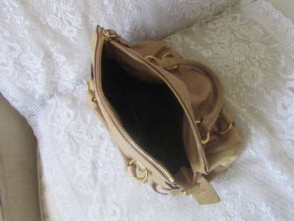 Beige handbag with gold accents on a textured white surface