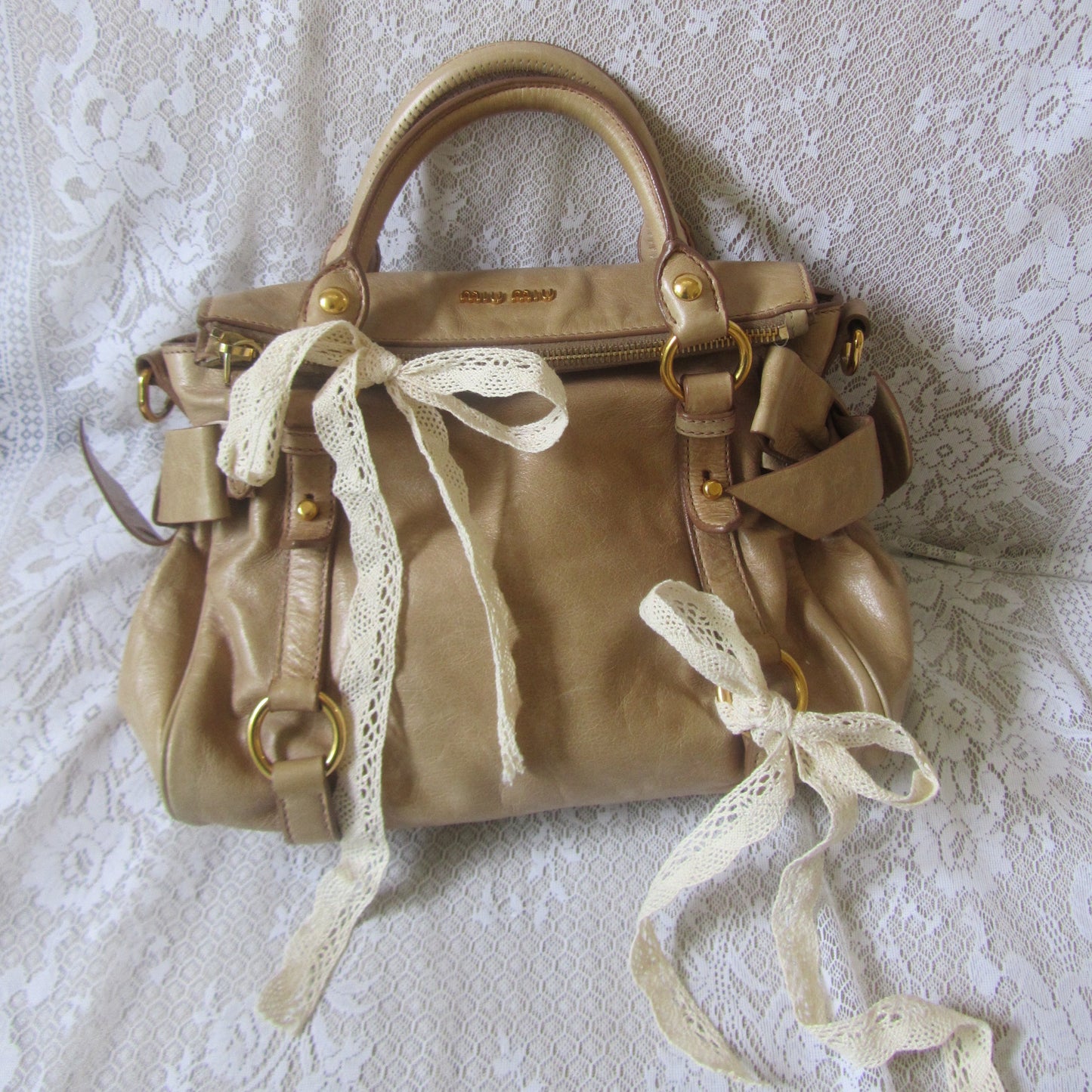 Gold handbag with lace details on a textured white surface