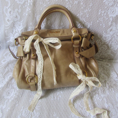 Gold handbag with lace details on a textured white surface