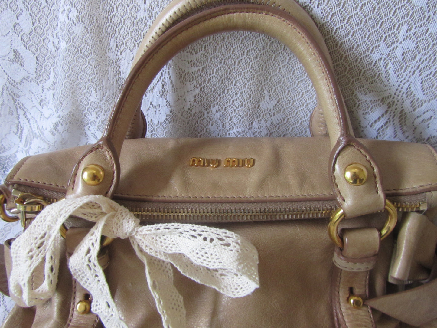 Beige handbag with lace detail on a textured white background