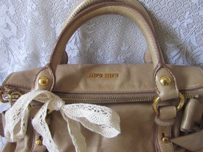 Beige handbag with lace detail on a textured white background