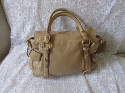 Beige handbag with gold accents on a white lace background