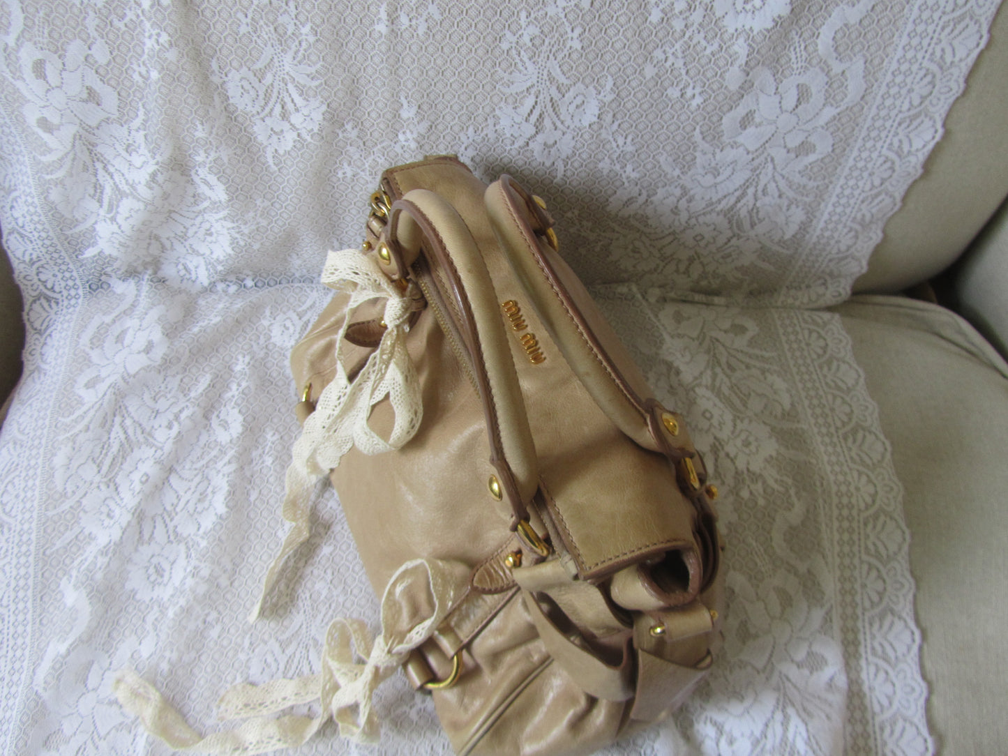 Beige handbag with decorative elements on a white lace fabric background