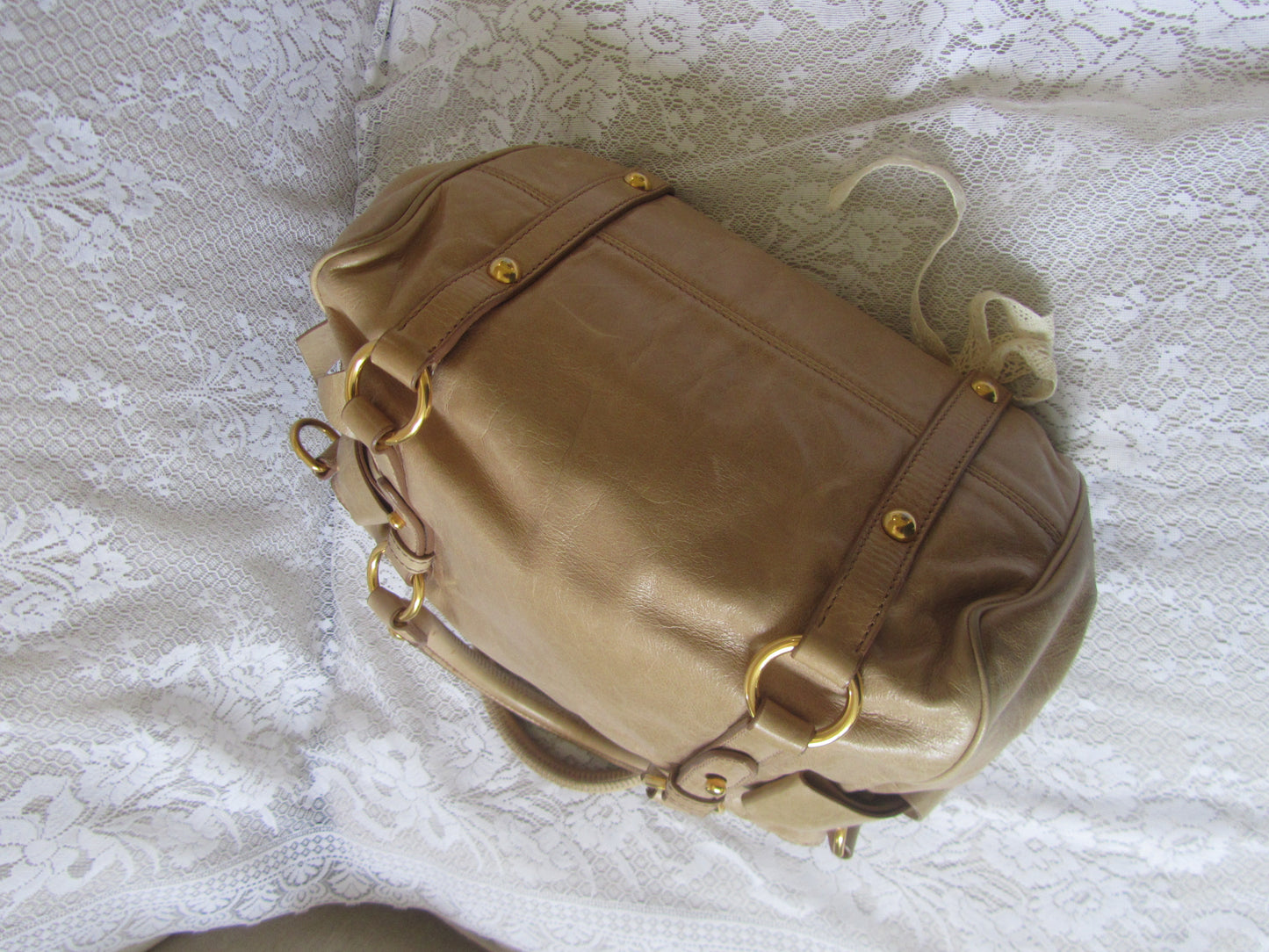 Brown leather bag with gold accents on a textured white surface