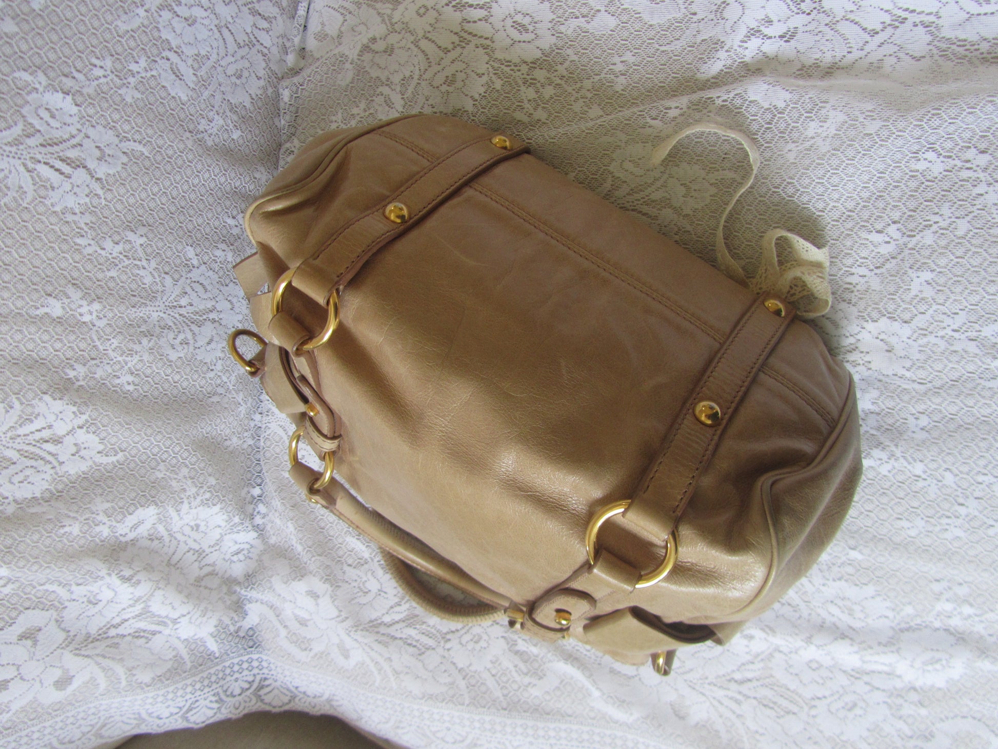 Brown leather bag with gold accents on a textured white surface