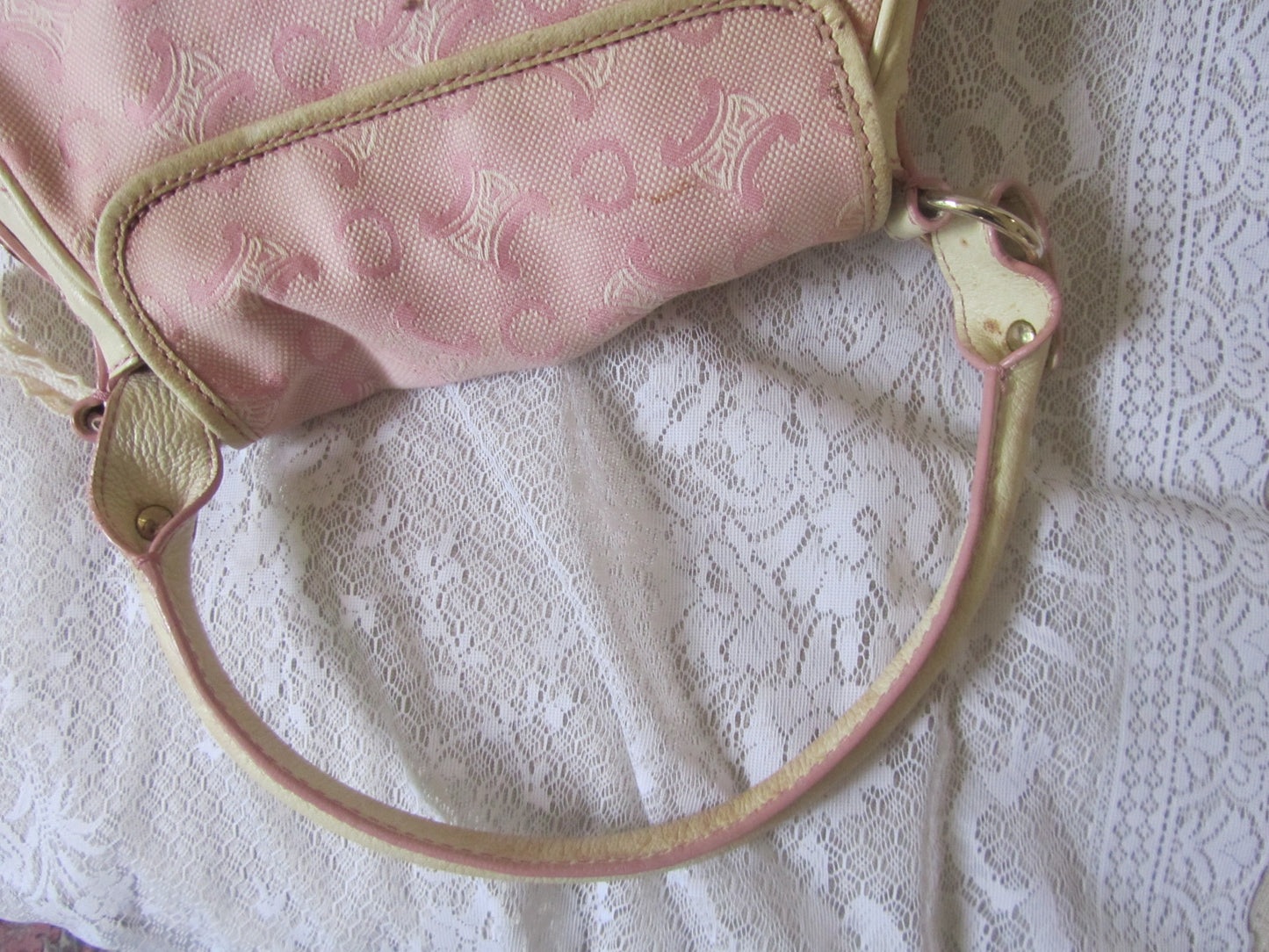 Pink handbag with gold accents on a lace background