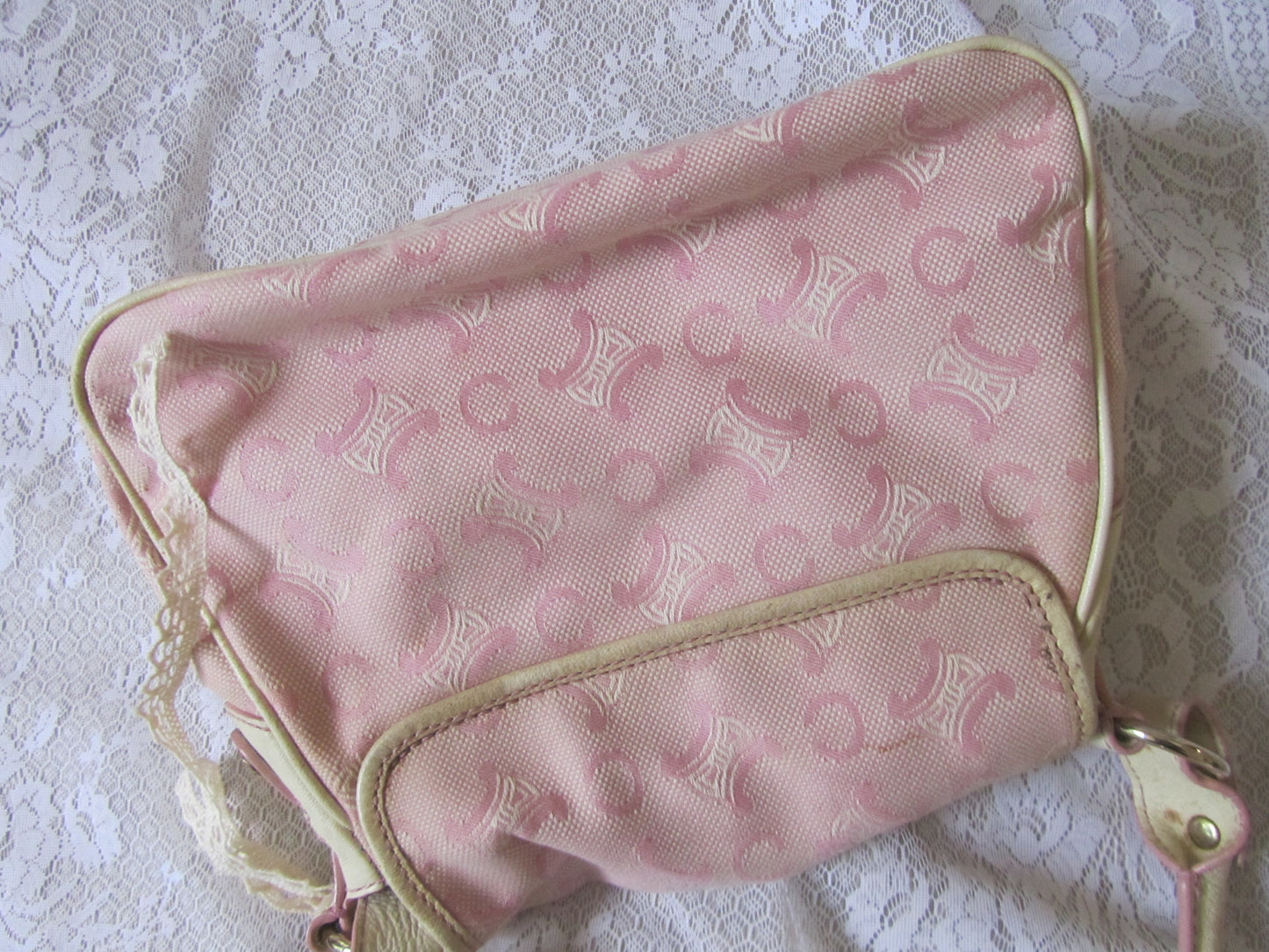 Pink patterned bag with gold trim on a lace background