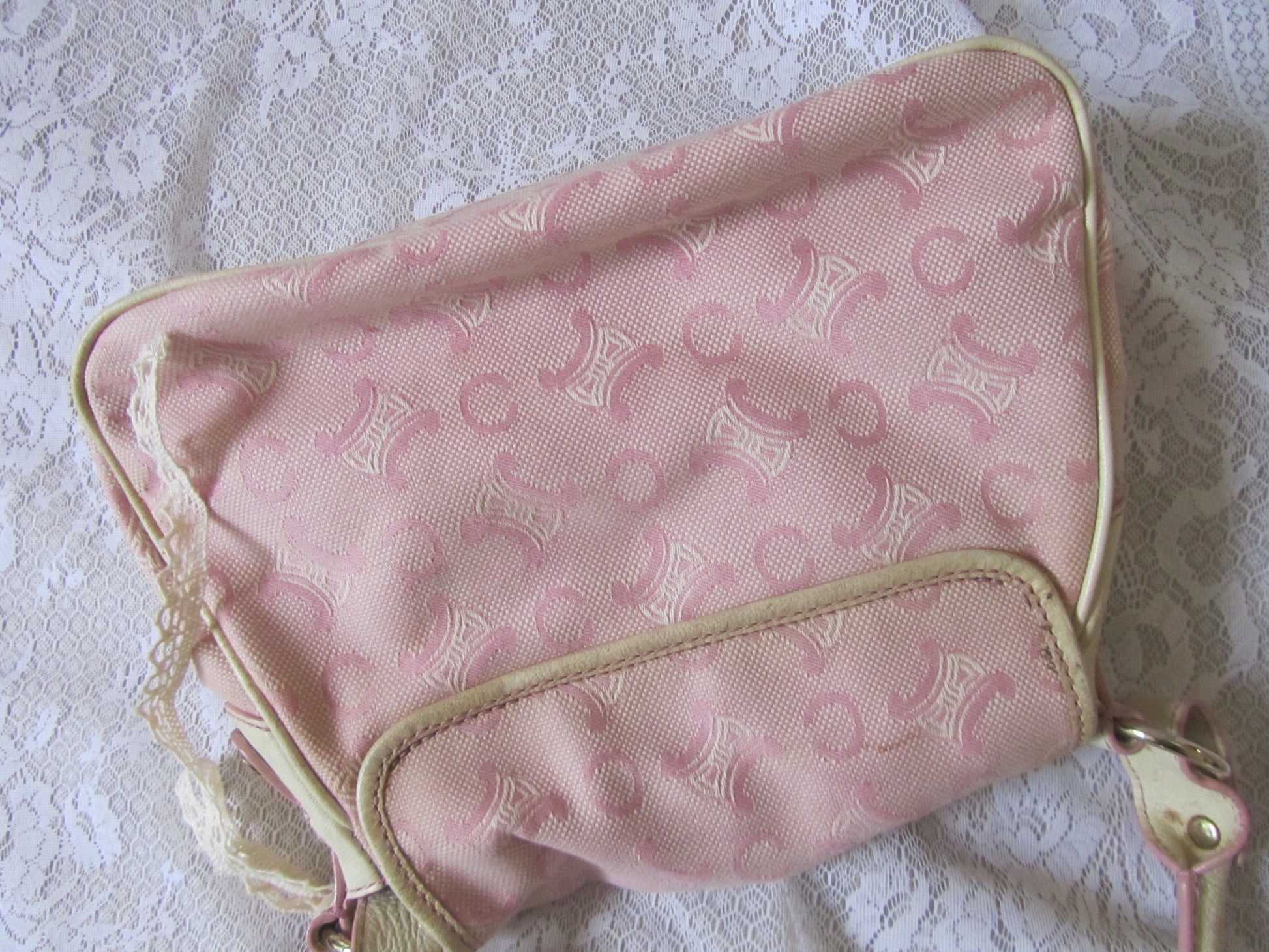 Pink patterned bag with gold trim on a lace background